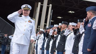 World War II veteran in uniform passing a line of saluting military personnel