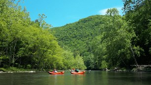 Canoers on a gentle river near mountains