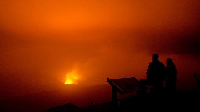 Silhouette of two people watching lava eruption