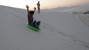 Woman sledding down a sand dune