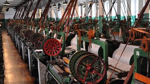 Green and red looms lined up in long room