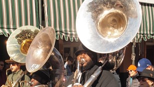 Tuba players playing their instruments while walking down New Orleans street.
