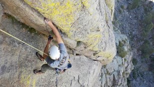 Rock climber setting up acoustic equipment while climbing