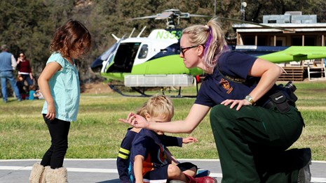 Kids talk with a firefighter at a helicopter base.