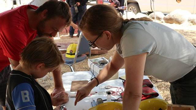 A fire scientist shares information with a family about fires in national parks.