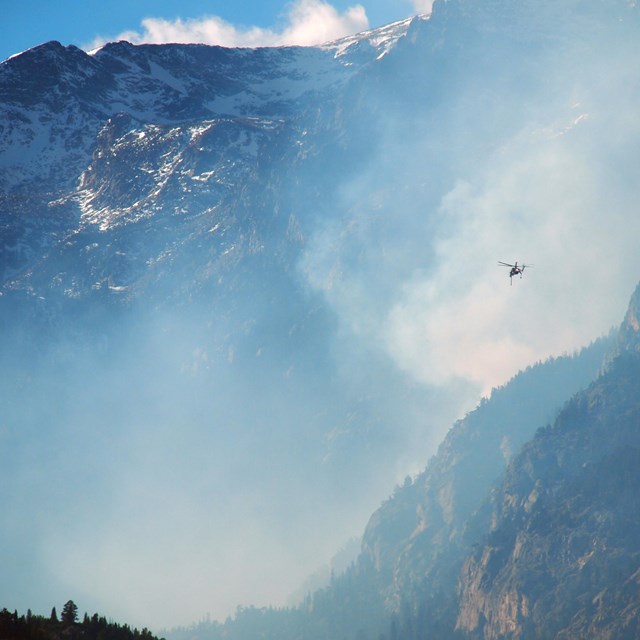 Helicopter flying over a wildland fire in the mountains