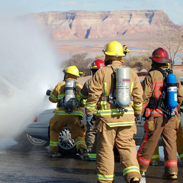 NPS firefighters use a fire hose to put out a vehicle fire during training