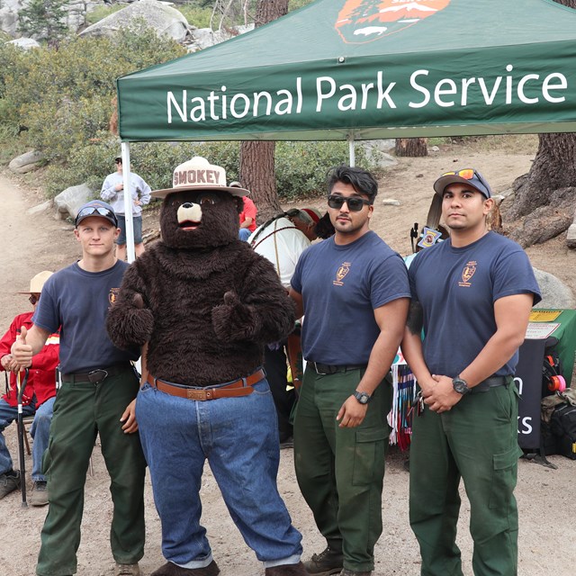 Firefighters stand with Smokey Bear at an outreach event. 