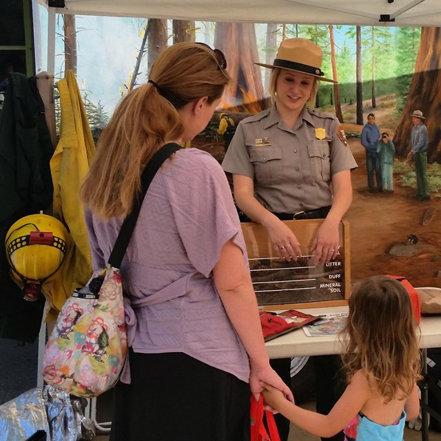 A park ranger talks with a family about fire in a national park. 