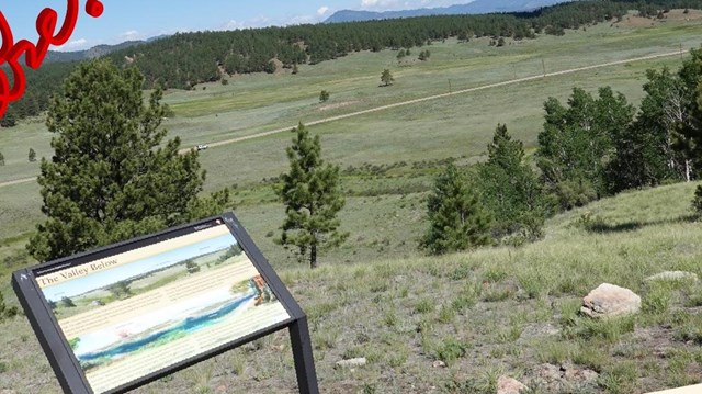 Photograph of a valley overlook with a wayside panel at front.