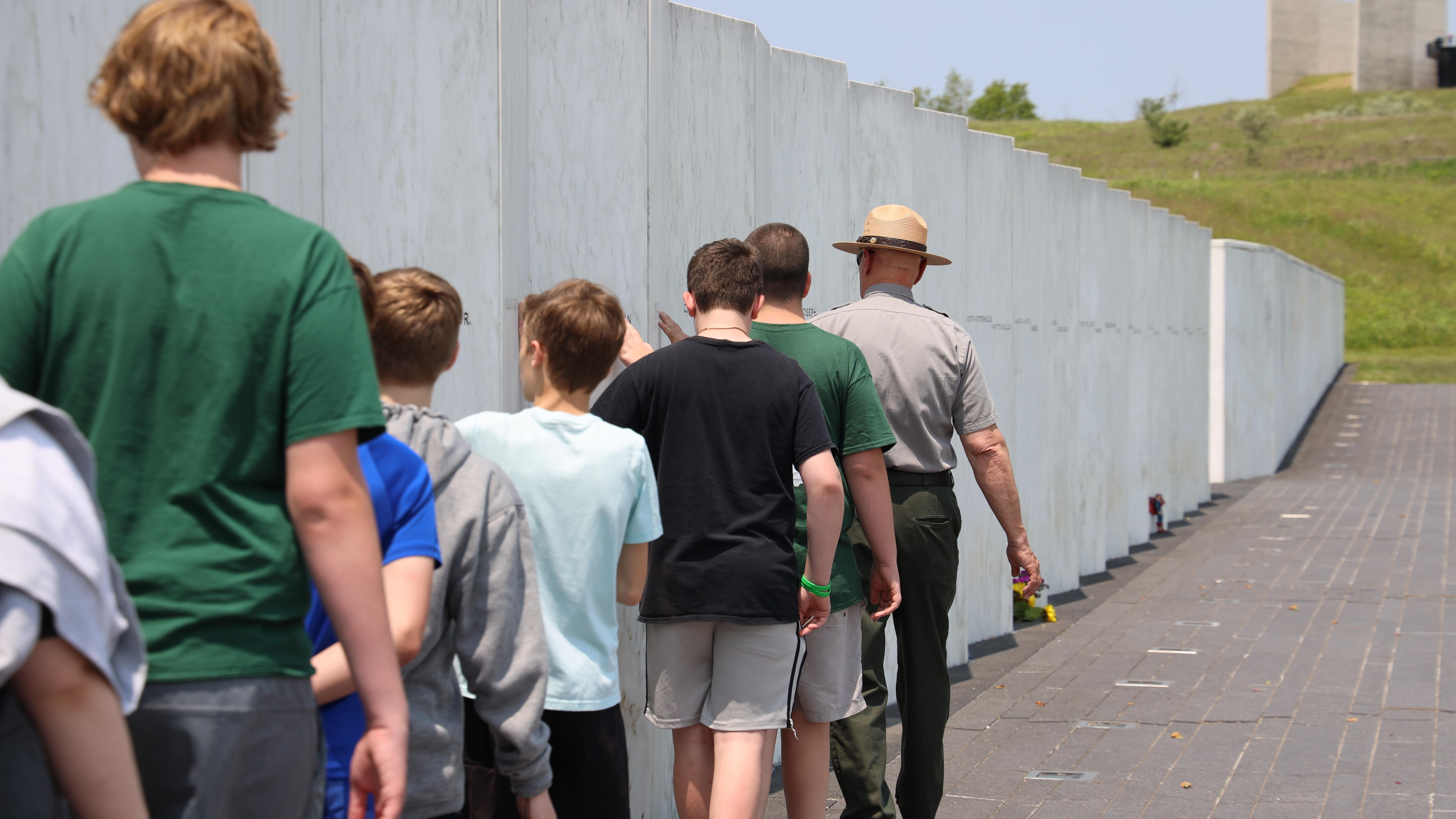 A ranger walking along the Wall of Names with a group of students.