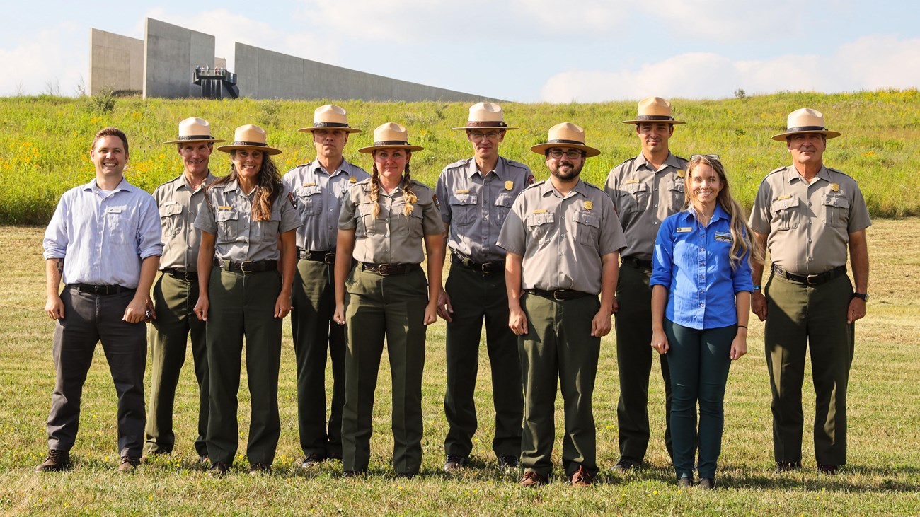 A group of staff stand in front of the Visitor Center.