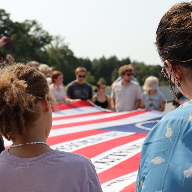 Visitors learning how to fold an American flag at the Memorial Plaza.