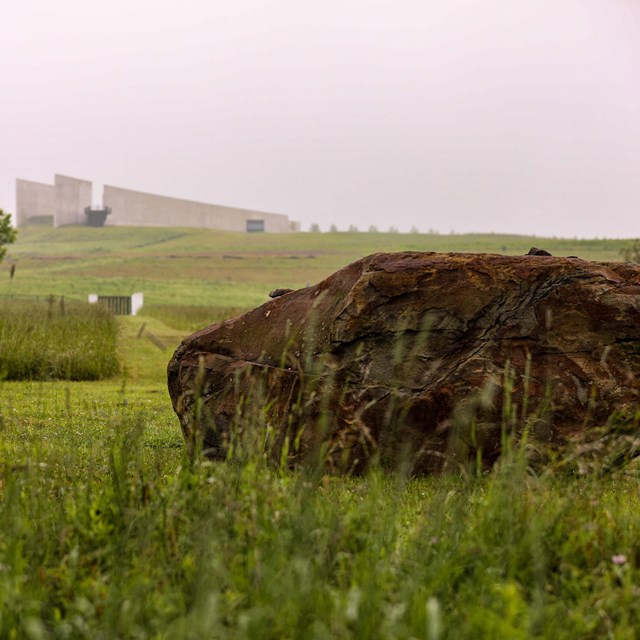 The boulder on the crash site with the Ceremonial Gate and Visitor Center shown from a distance.