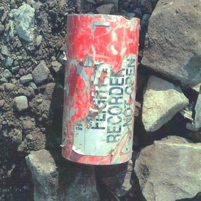 A image shows the recovered flight data recorder found at the crash site