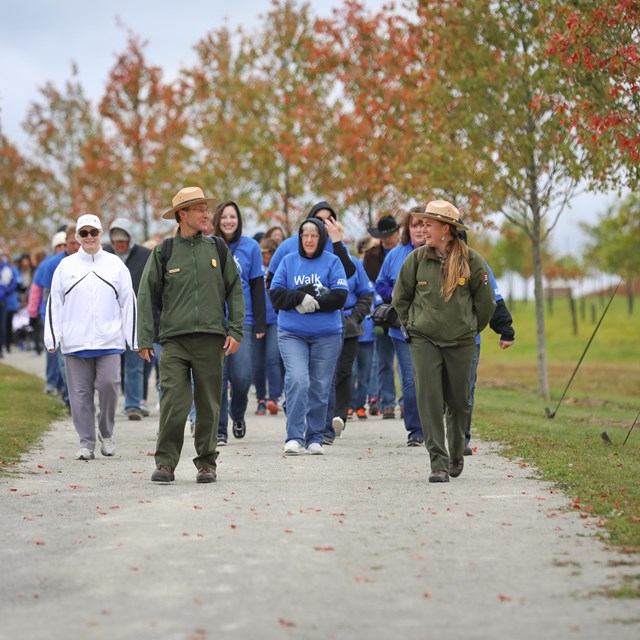 Two rangers leading a group down a trail.