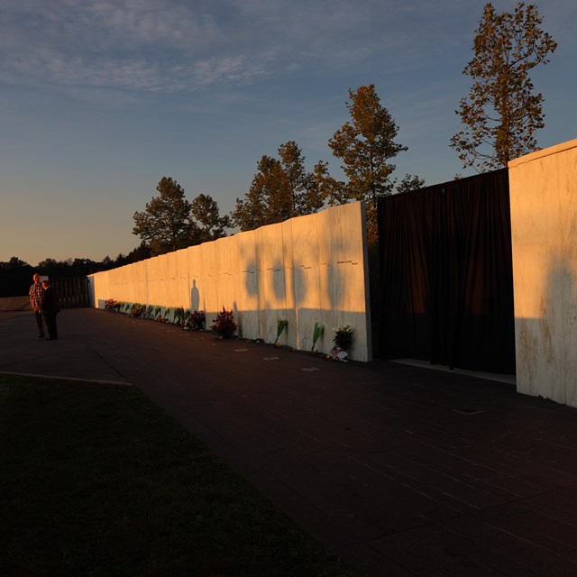 A soft orange light illuminates a white marble wall at sunrise.