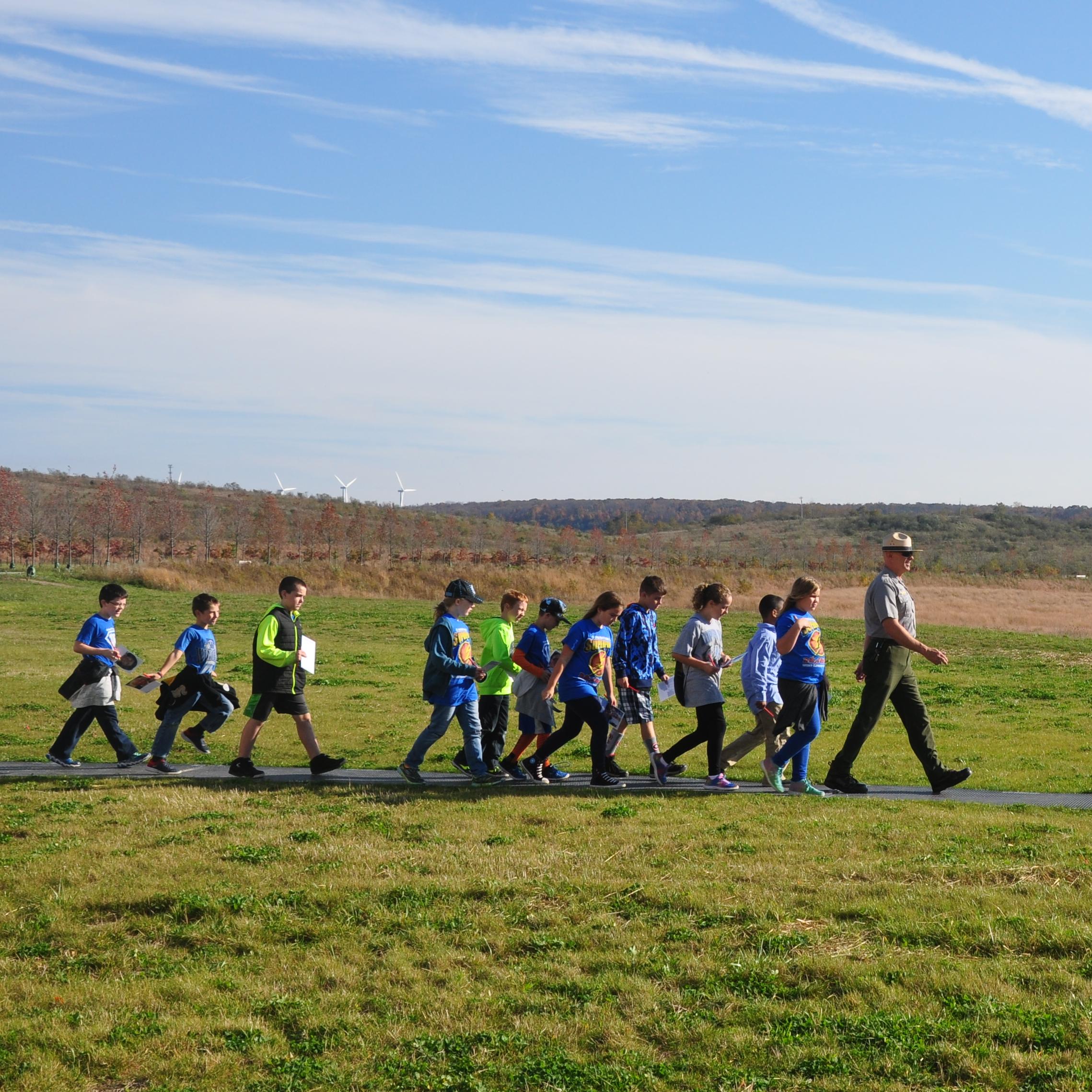 A ranger leads a group of school students on a trail.