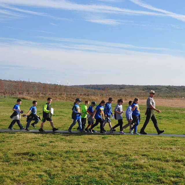 A ranger leads a group of school students on a trail.