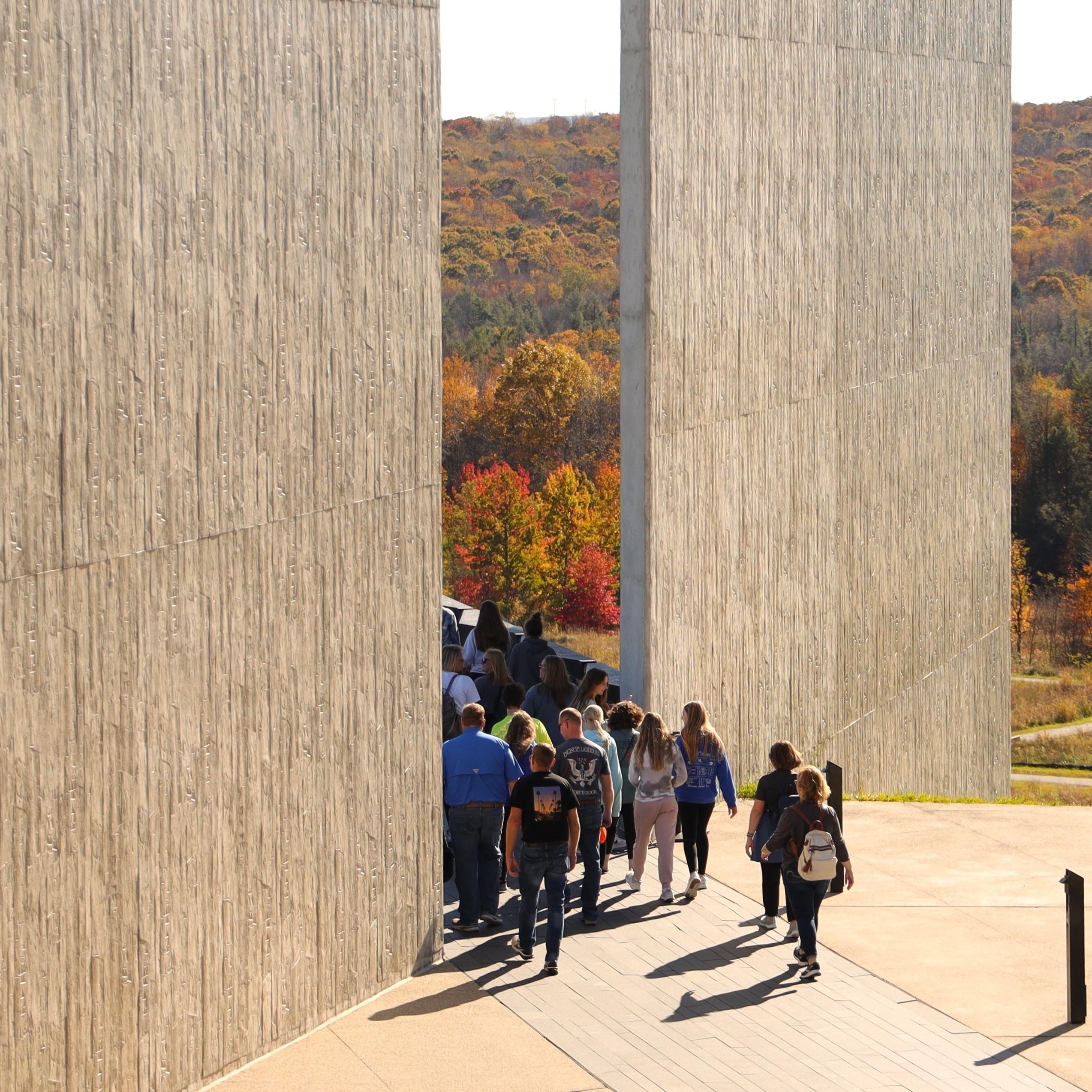 A group of students walk on a walkway by the visitor center