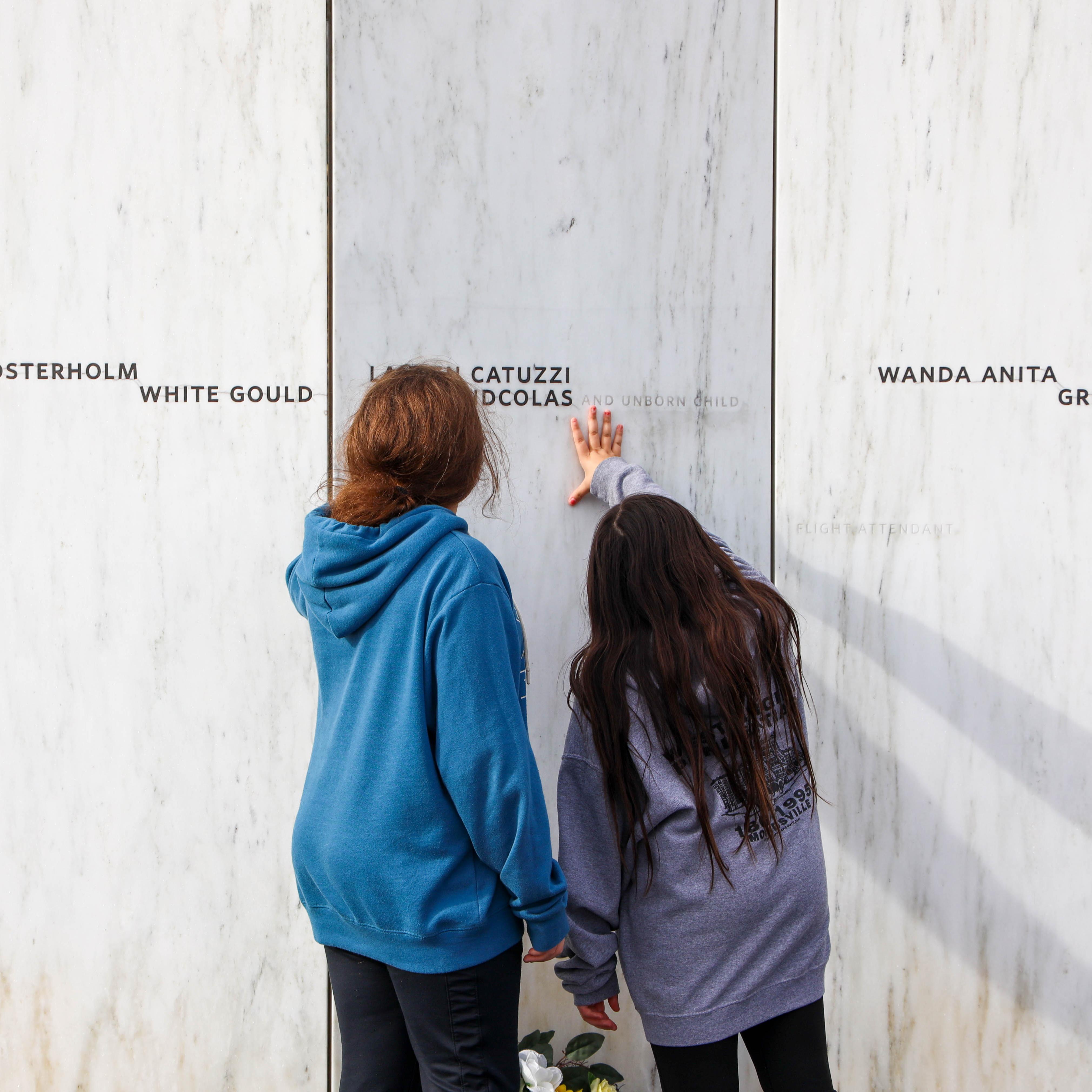 A group of students touch the Wall of Names