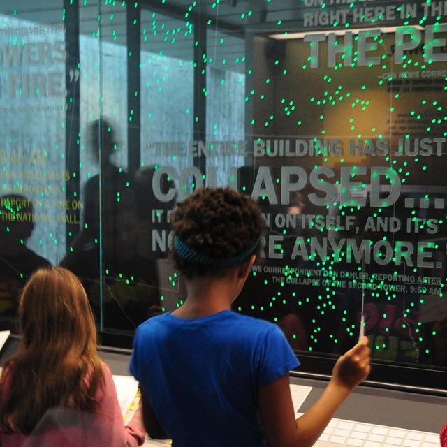 Students standing in front of exhibit with dots indicating the plane over the United States.