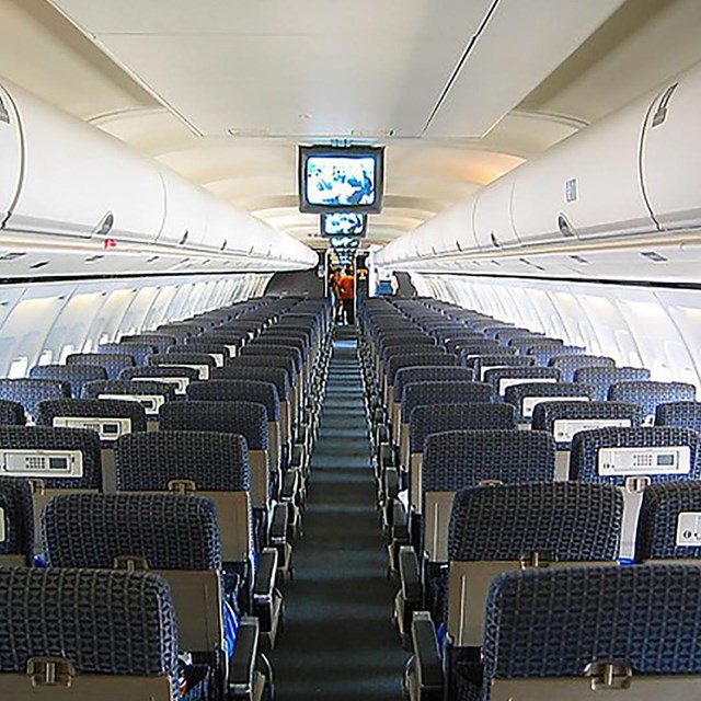 An interior image of a plane with airfones on the seatbacks 