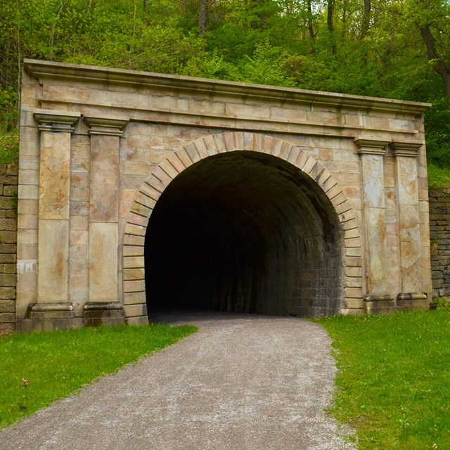 View into the entrance of a stone cut railroad tunnel.