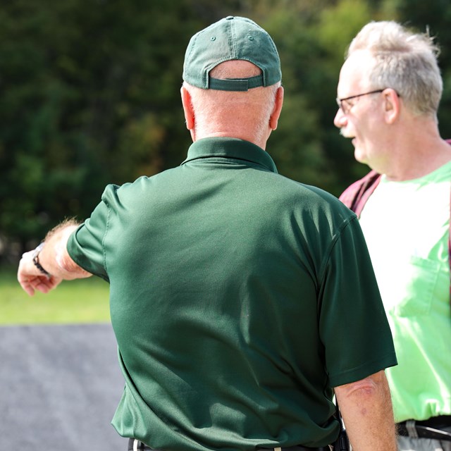 A volunteer pointing and speaking to a visitor.
