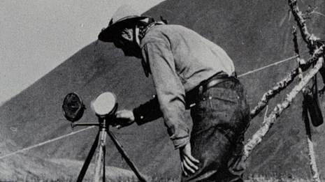 Black and white photo of two men looking at instruments on tripods