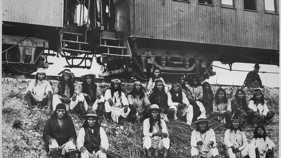 Chiricahua Apaches sit outside of a railway car bound for Florida