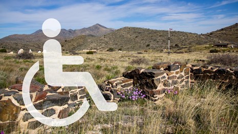 A handicap symbol with mountains and rock foundations in the background.