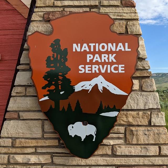 NPS arrowhead on rock wall.