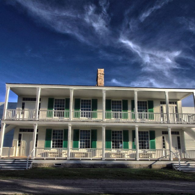 A large white building with two stories and white pillars on both levels. 