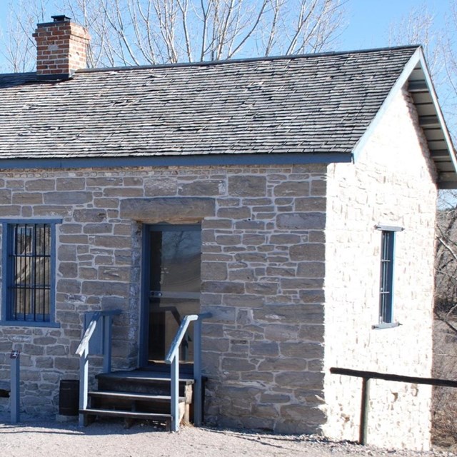 Small stone buildings with two doors and for windows. Small brick chimney out of the roof