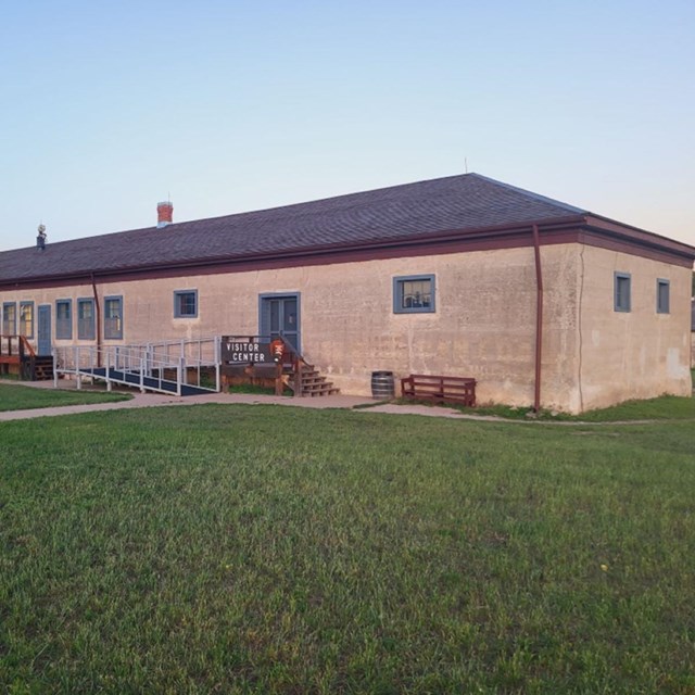 Long lime grout building with a blue roof along with blue trimmed windows.  