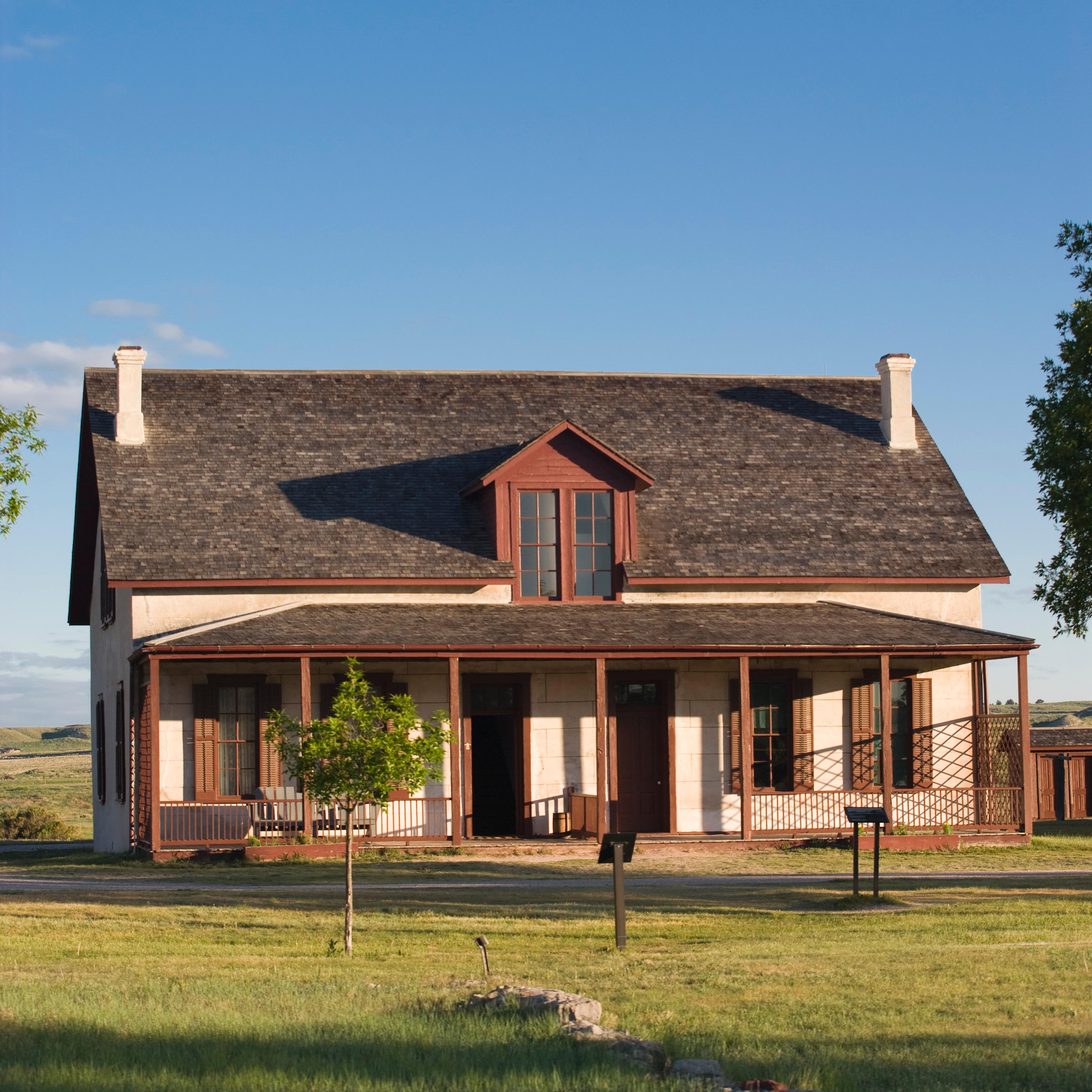An adobe style two story building. A red porch with red pillars on the outside. 