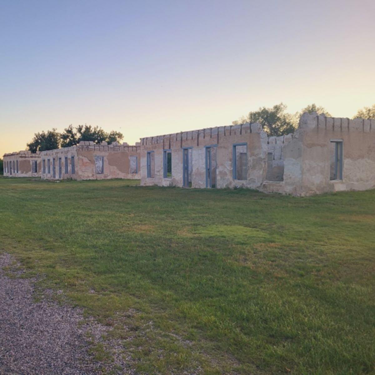 Adobe walls standing in a grassy field 