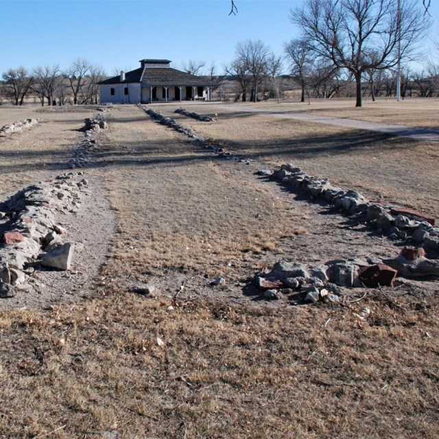 Piles of lined rubble are in a rectangle formation on a grassy ground. 