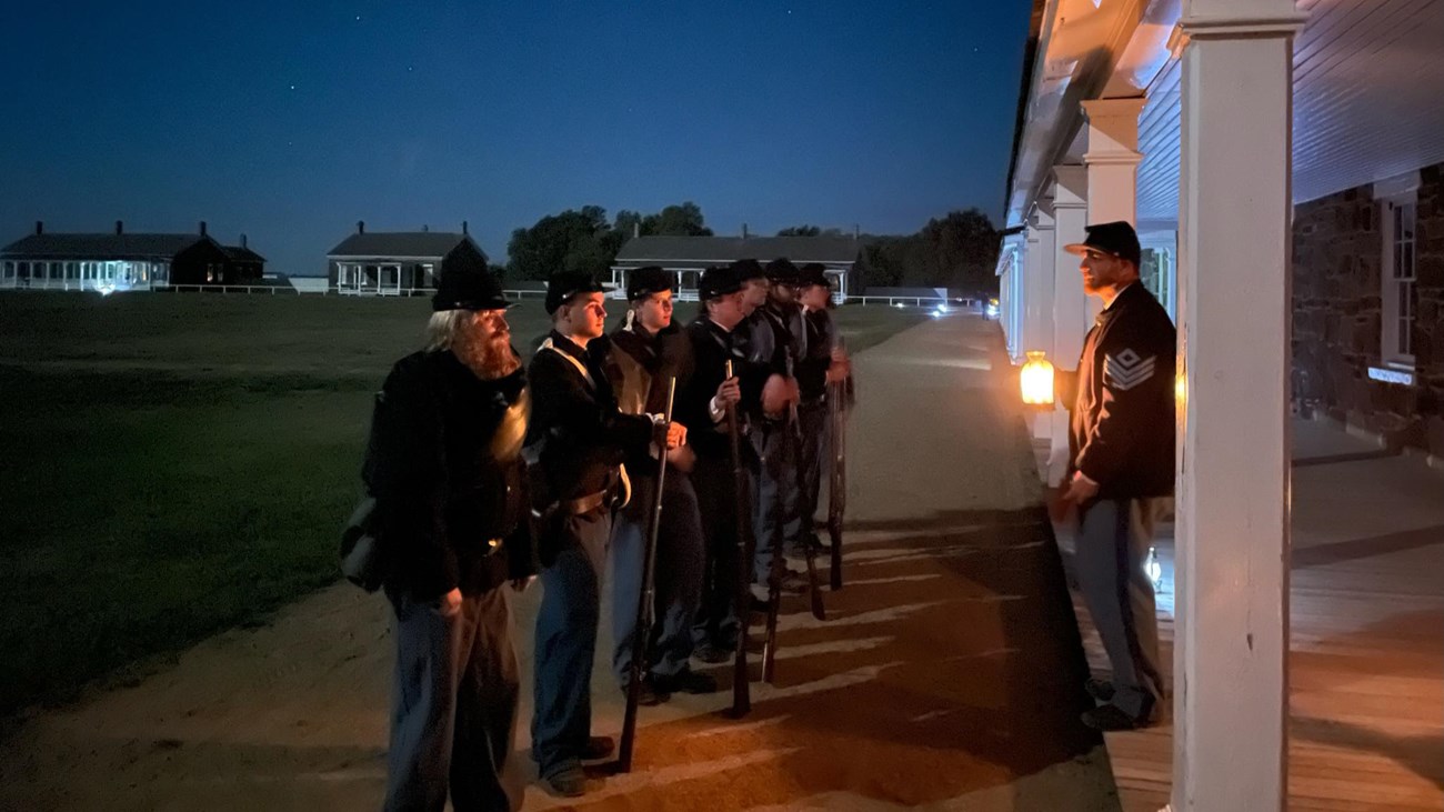 Soldiers line up in front of the barracks after dark.