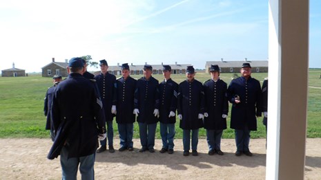 Volunteer soldiers stand in ranks in front of the barracks.
