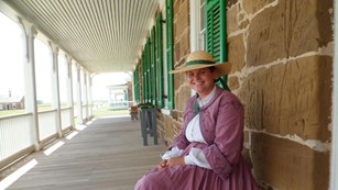 Volunteer in 19th century women's clothing on the porch of Officers' Row.