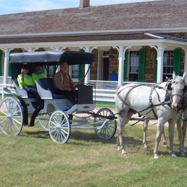 Horse drawn carriage in front of sandstone building.