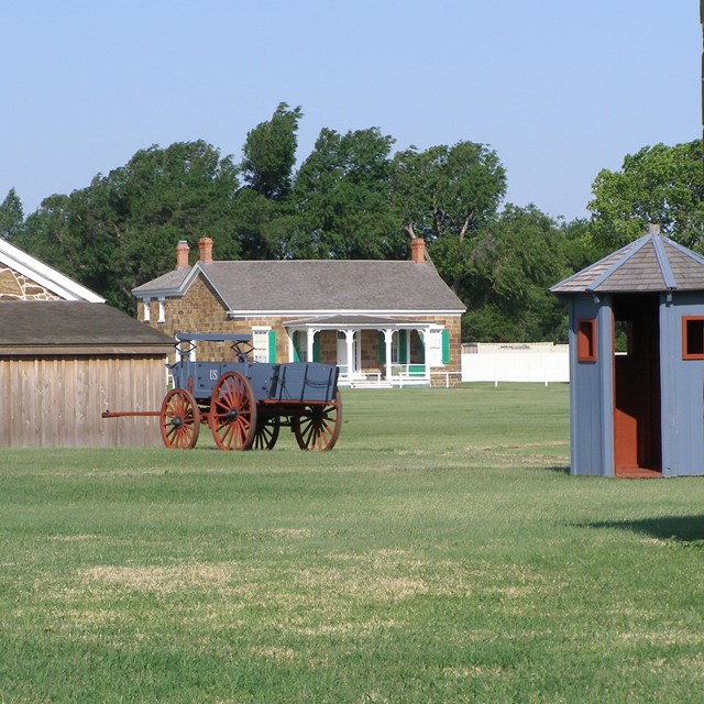 Image of sandstone buildings with reproduction army wagon in middle.