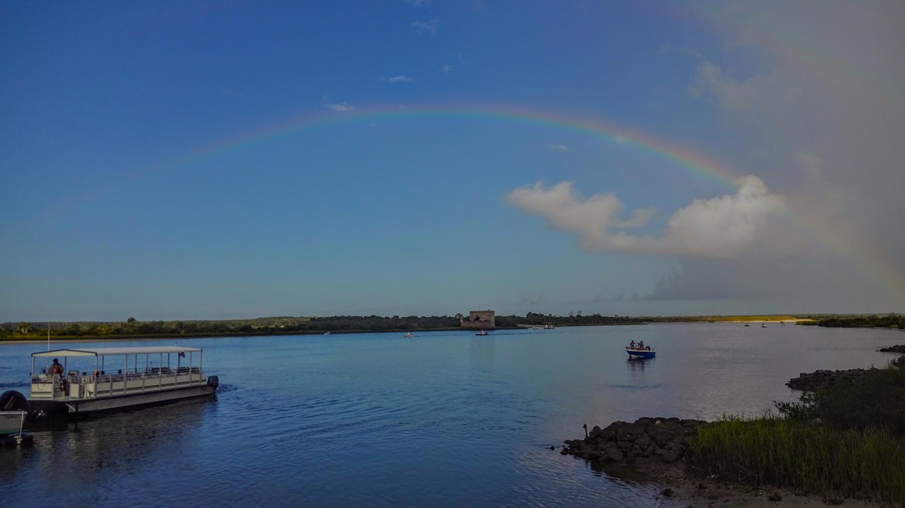 Rainbow over river. Fort and Ferry boat