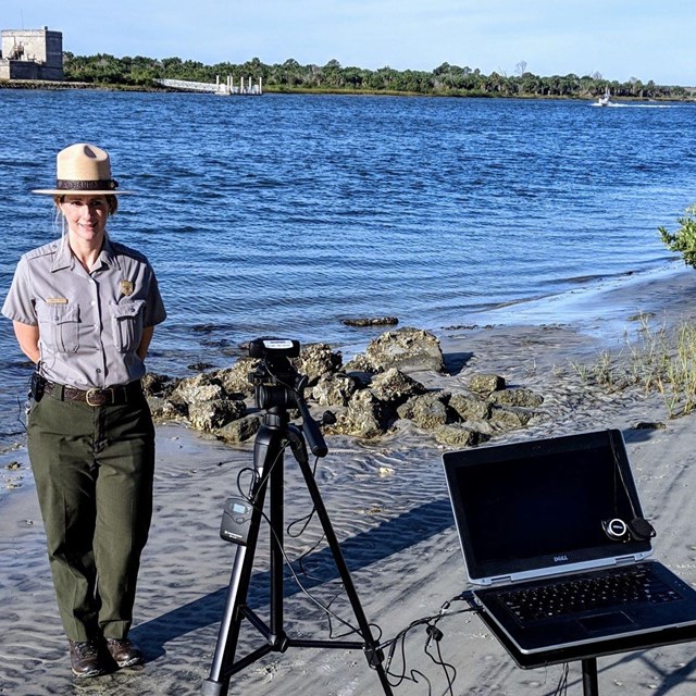 Ranger with a computer and camera setup with fort in background. 