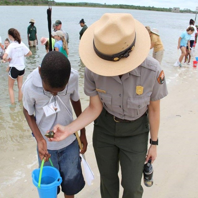 Ranger with student in the water. 