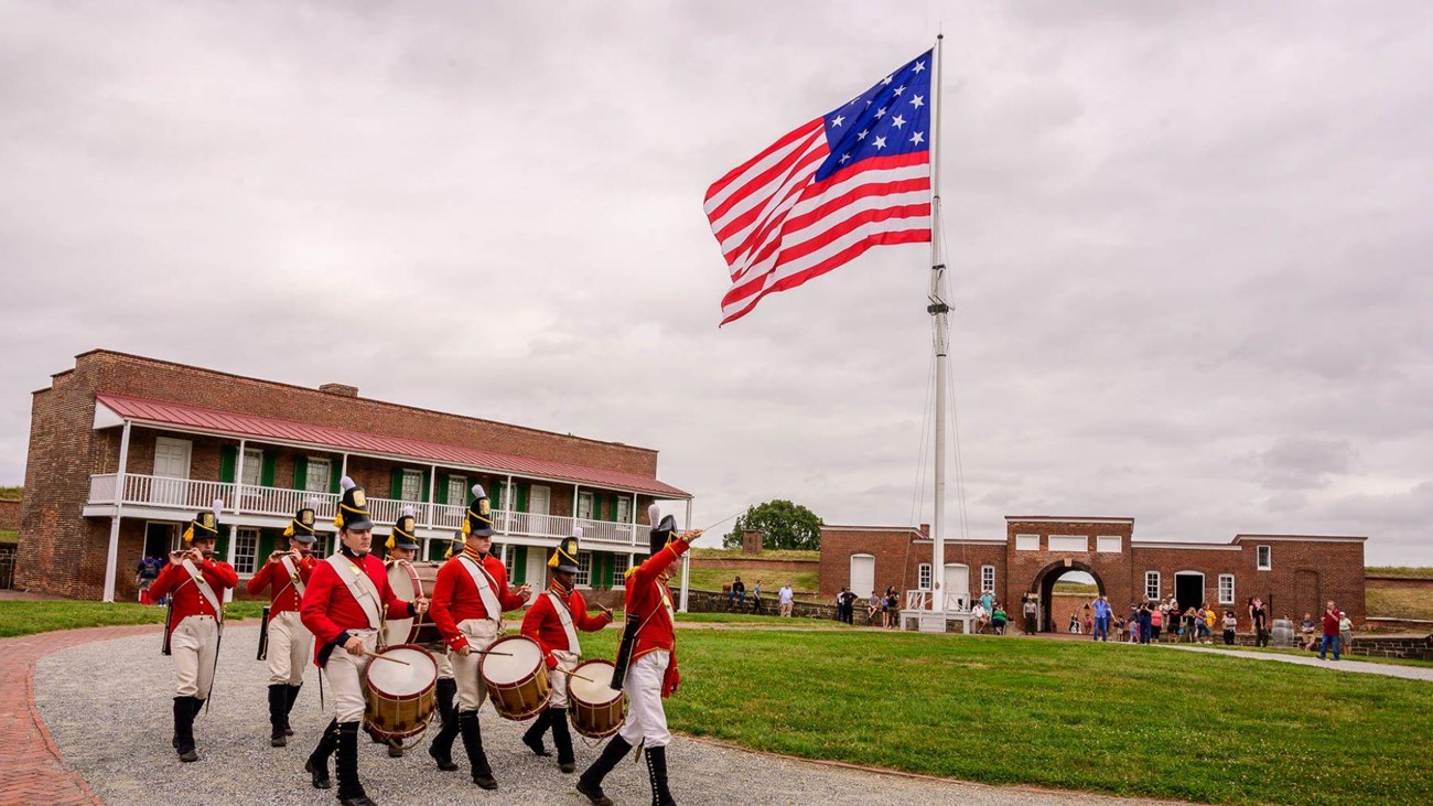 A picture of Living History dressed up in period fife and drum clothing in the fort's parade ground.