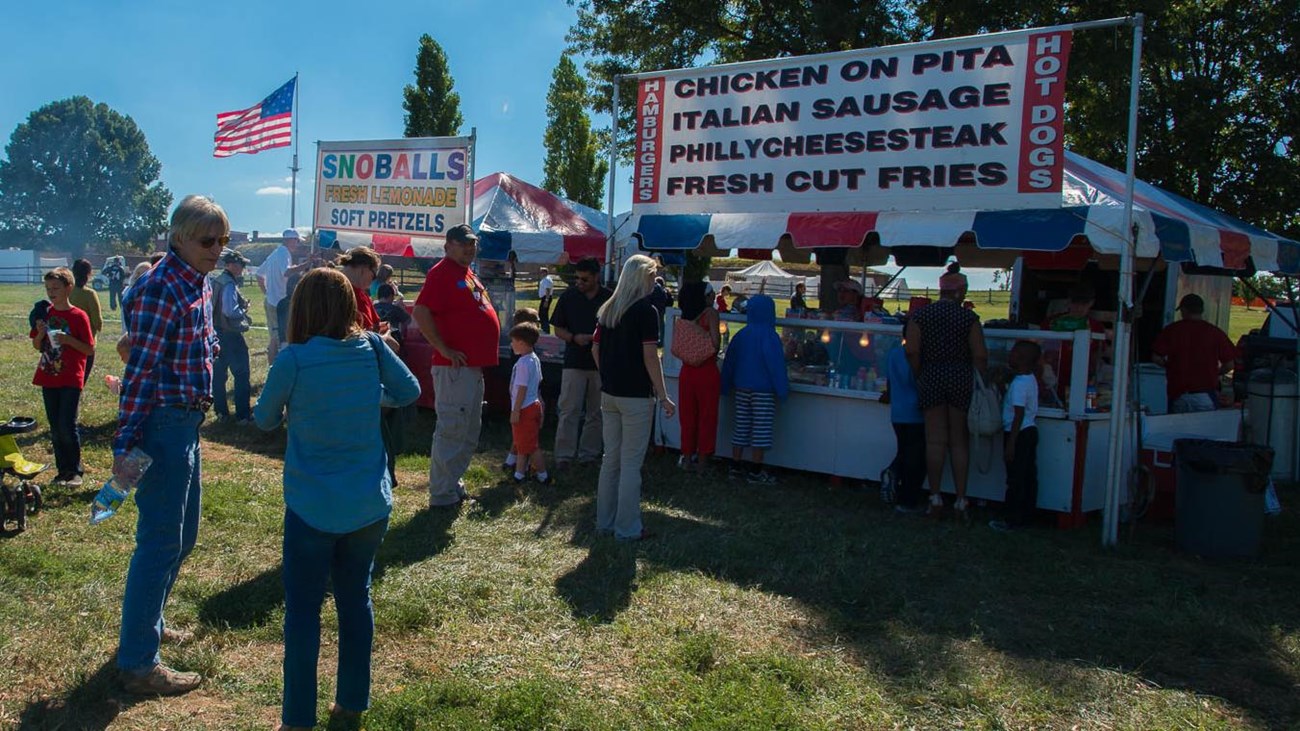 Food stands with visitors at the park.