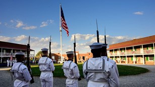 Five members of the Navy Tattoo facing the flag pole in the star fort.